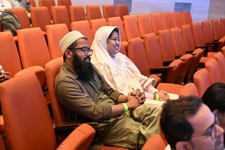 Two colleagues seated in an auditorium at an event