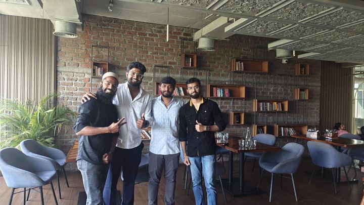 A group of colleagues standing together in a brick-walled co-working space