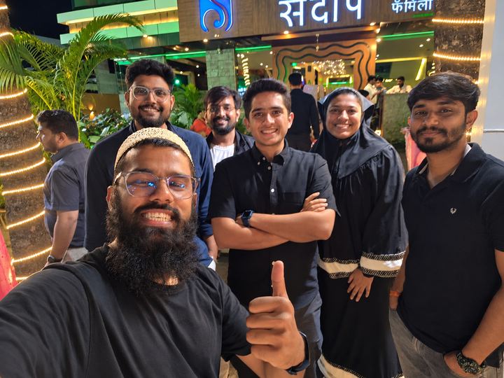 Colleagues in a group selfie outside a restaurant at night