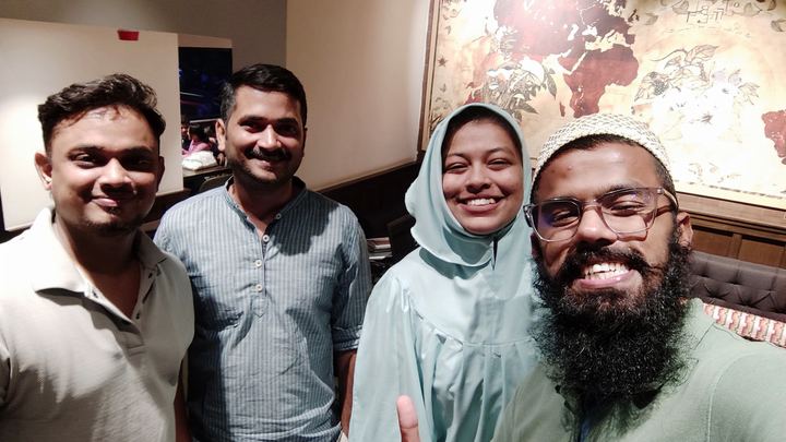Two colleagues posing with two guests in front of a wall map